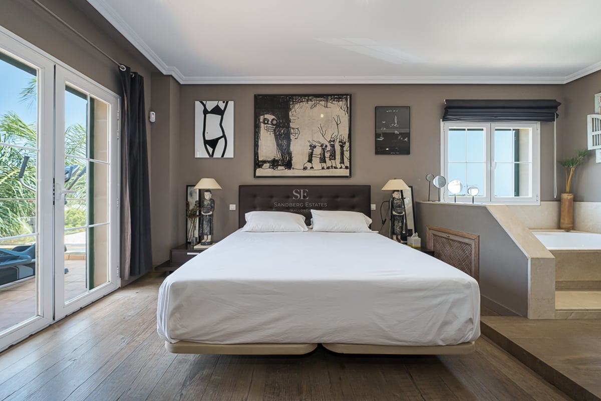 Chambre moderne avec lit double, parquet en bois et jacuzzi intégré à côté des portes-fenêtres.