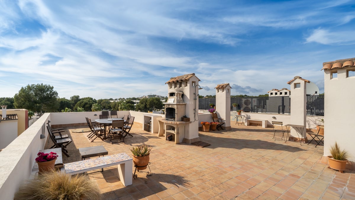 Grande terrasse sur le toit avec carrelage en terre cuite, table à manger et barbecue en pierre intégré.