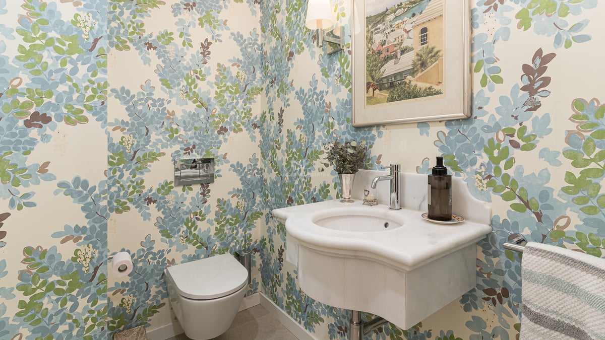 Toilettes invités avec papier peint floral, vasque en marbre sculpté et WC suspendu.