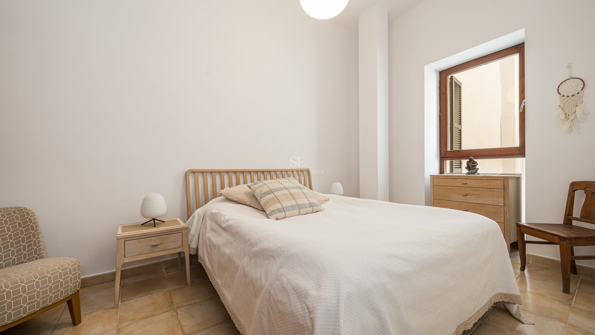 Chambre minimaliste avec sol en terre cuite, meubles en bois clair et fenêtre à cadre en bois naturel.