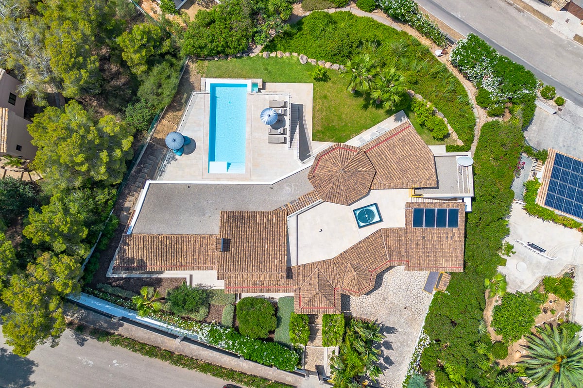 Vue extérieure d'une villa moderne avec piscine à débordement, jardin et vastes terrasses. Design minimaliste avec grandes baies vitrées et architecture élégante.