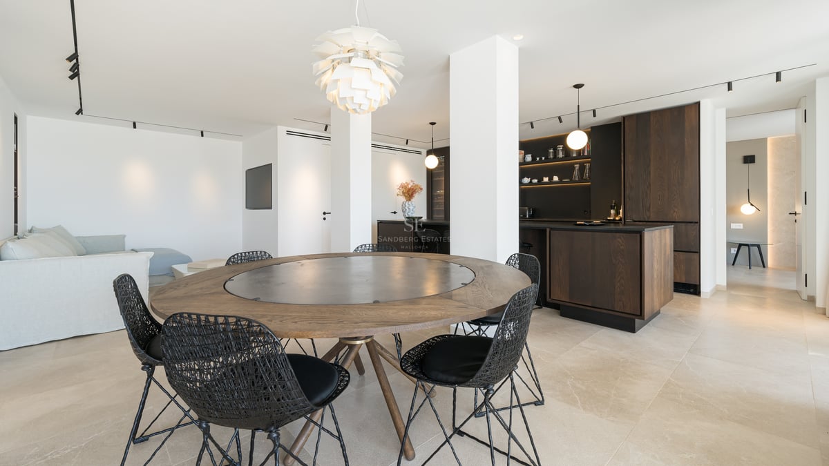 Table à manger ronde en bois avec chaises tressées noires dans un espace de vie moderne ouvert.