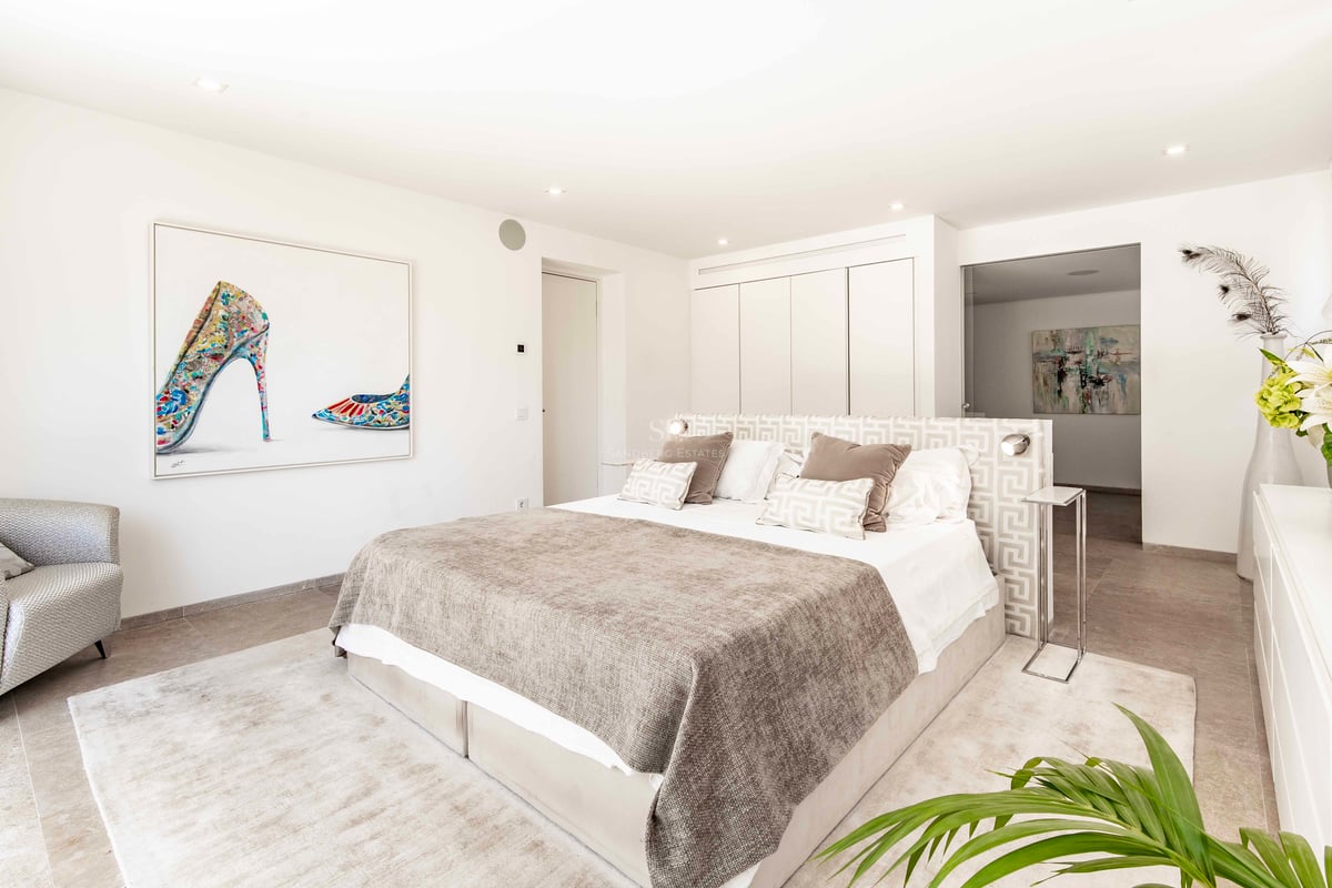 Chambre moderne et lumineuse avec lit king-size, tons neutres, armoires encastrées et art contemporain grand format.