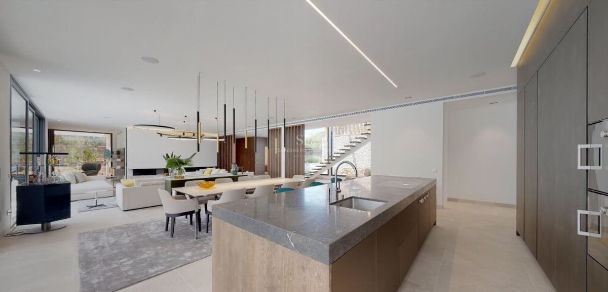 Cuisine contemporaine avec îlot en pierre grise, meubles en bois et coin repas avec luminaires design.