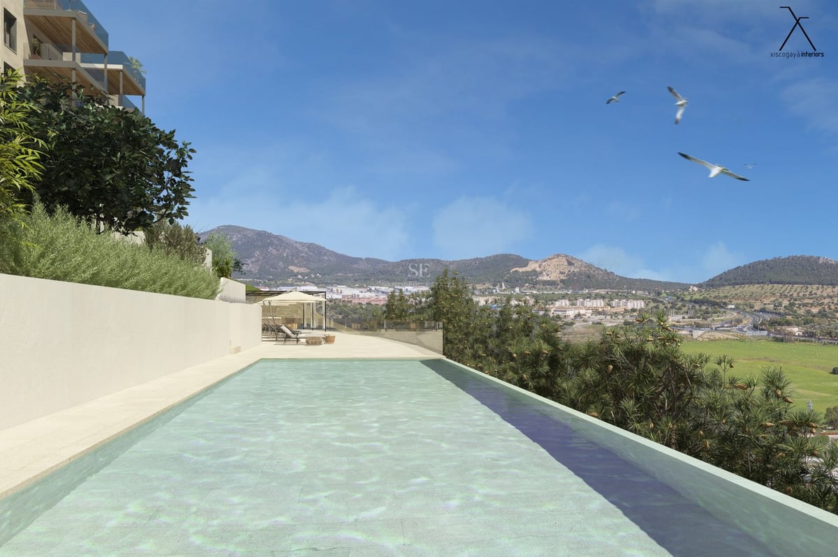 Piscine rectangulaire avec terrasse en pierre, surplombant une vallée et des montagnes sous un ciel bleu.