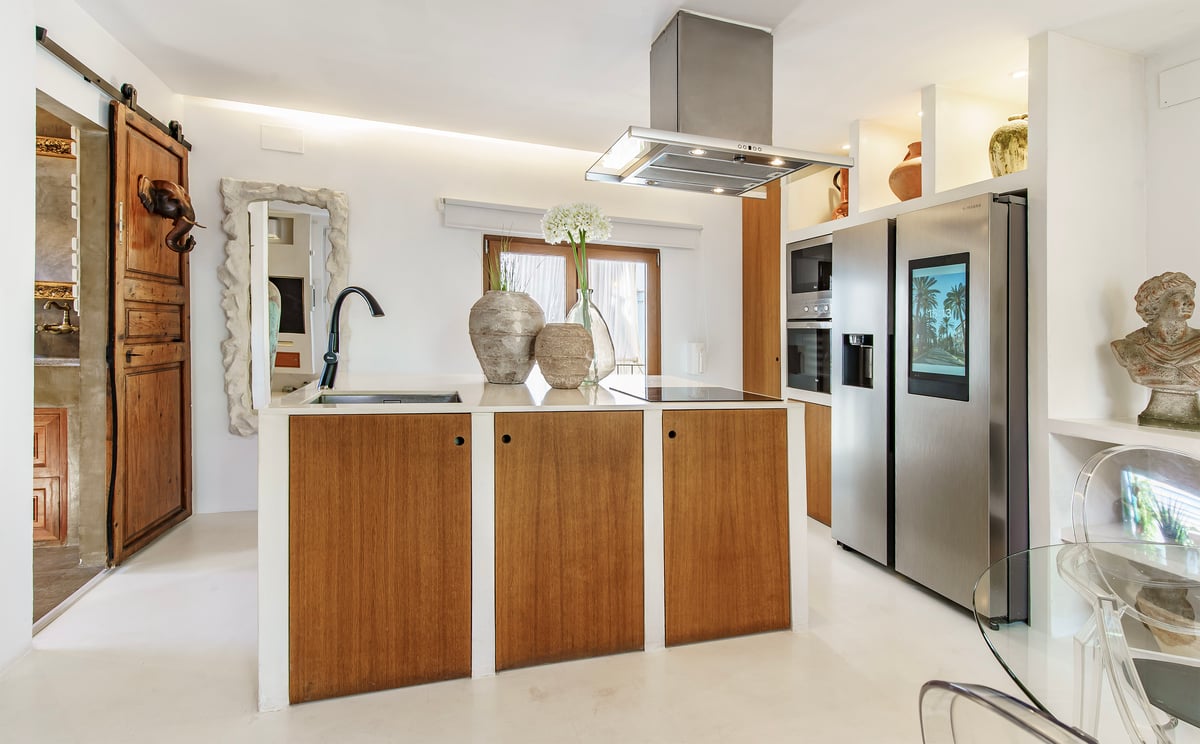 Cuisine contemporaine avec îlot en bois, plans de travail blancs et réfrigérateur intelligent en inox.