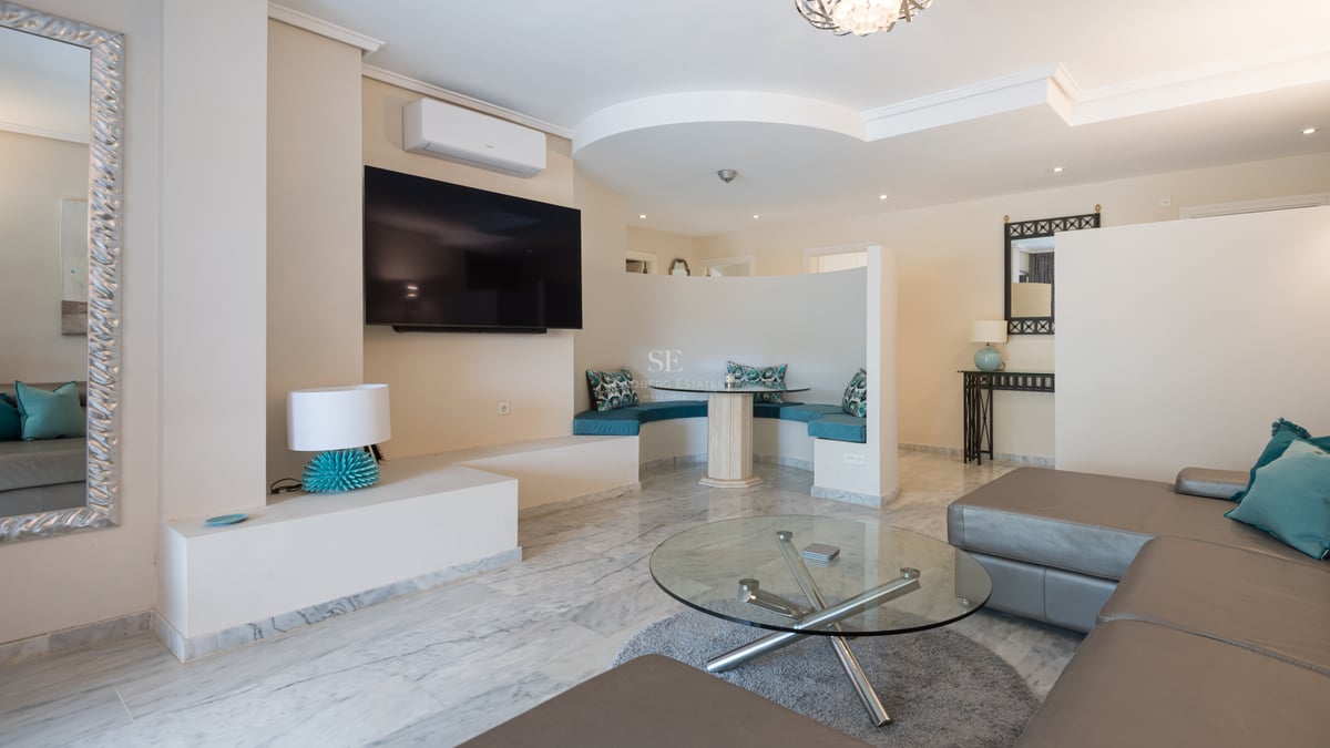Salon moderne avec sol en marbre, canapé en cuir et un coin petit-déjeuner incurvé avec coussins turquoise.