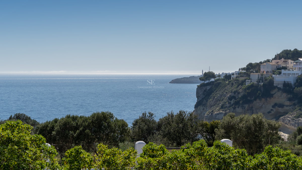 Vue sur la côte avec des maisons blanches sur une falaise et la mer bleue sous un ciel clair.