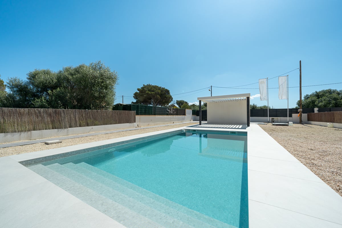 Piscine rectangulaire turquoise avec bordure blanche et pergola moderne sous un ciel bleu pur.