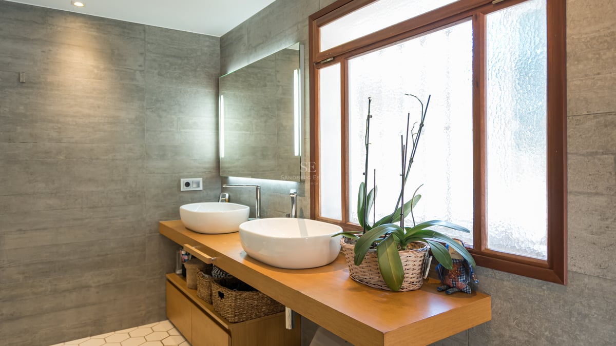 Salle de bain moderne avec deux vasques blanches sur meuble en bois, murs gris et miroir rétroéclairé.