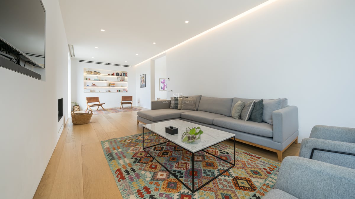 Salon moderne spacieux avec canapé d'angle gris, table en marbre et parquet en chêne clair.