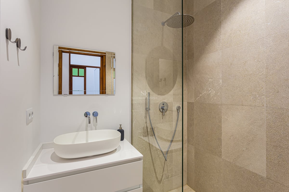 Salle de bain moderne avec une vasque blanche et une douche à l'italienne avec des carreaux en pierre beige.