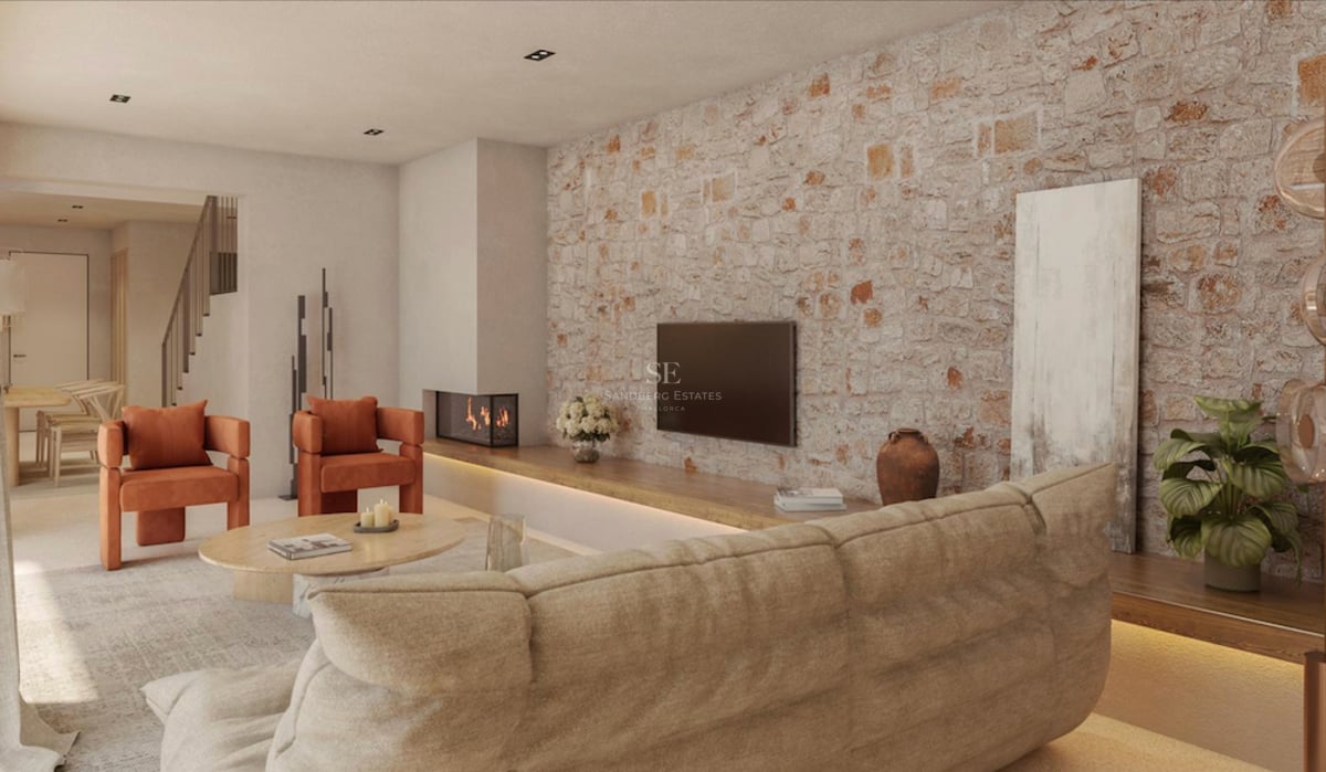 Salon moderne avec mur en pierre apparente, fauteuils orange, canapé beige et cheminée intégrée.