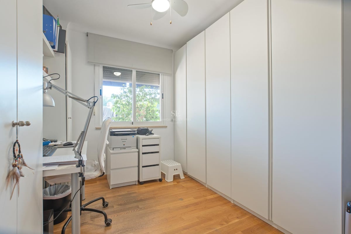 Pièce lumineuse avec de grands placards blancs, parquet en bois et un coin bureau près d'une fenêtre.