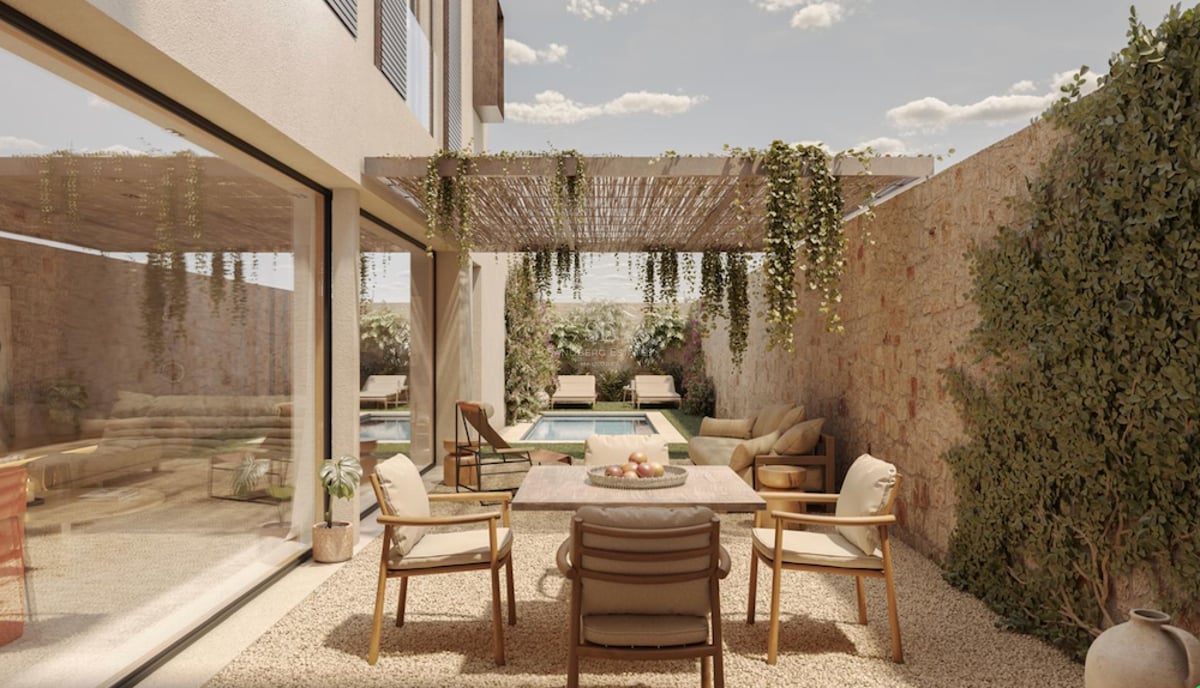 Terrasse moderne avec table à manger, mur en pierre, pergola végétalisée et piscine en arrière-plan.
