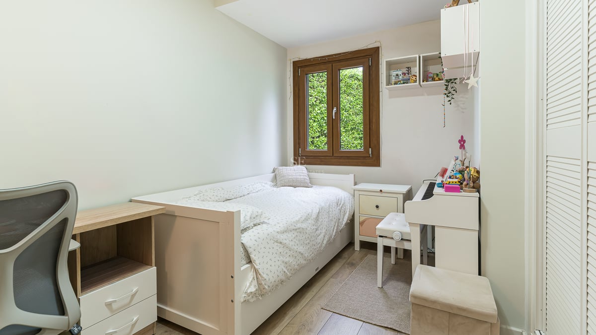 Chambre lumineuse avec lit simple blanc, bureau, piano numérique blanc et fenêtre donnant sur la verdure.
