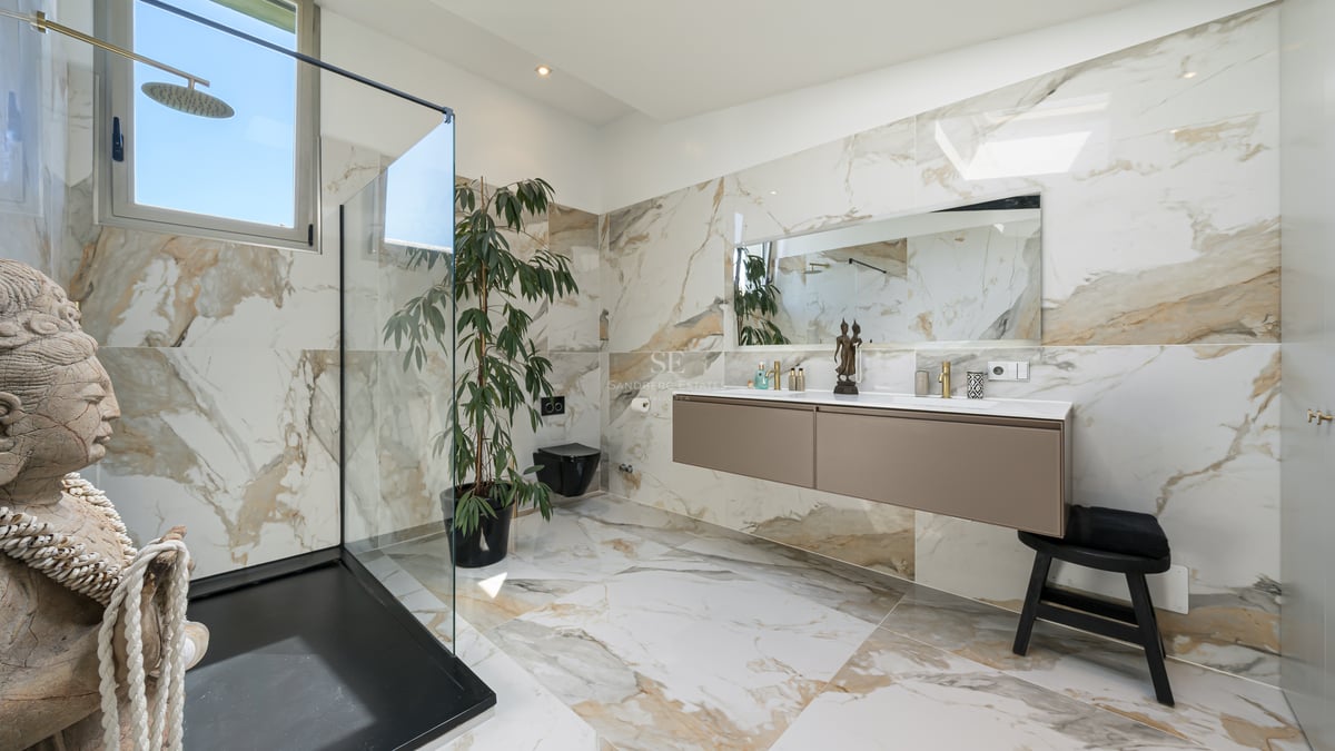 Salle de bain de luxe avec murs en marbre, douche à l'italienne et double vasque suspendue.