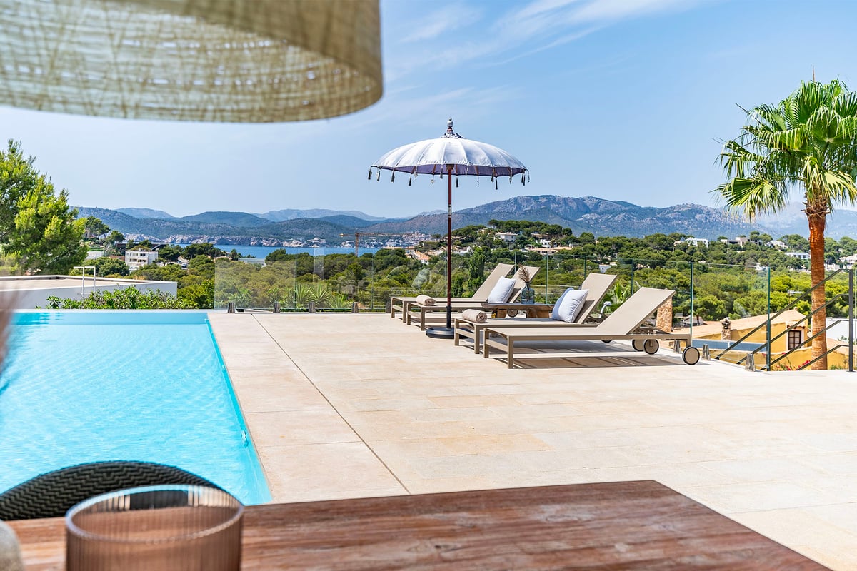Vue d'une luxueuse villa moderne avec piscine à débordement, vastes terrasses et vue panoramique sur la mer. Design minimaliste et élégant.