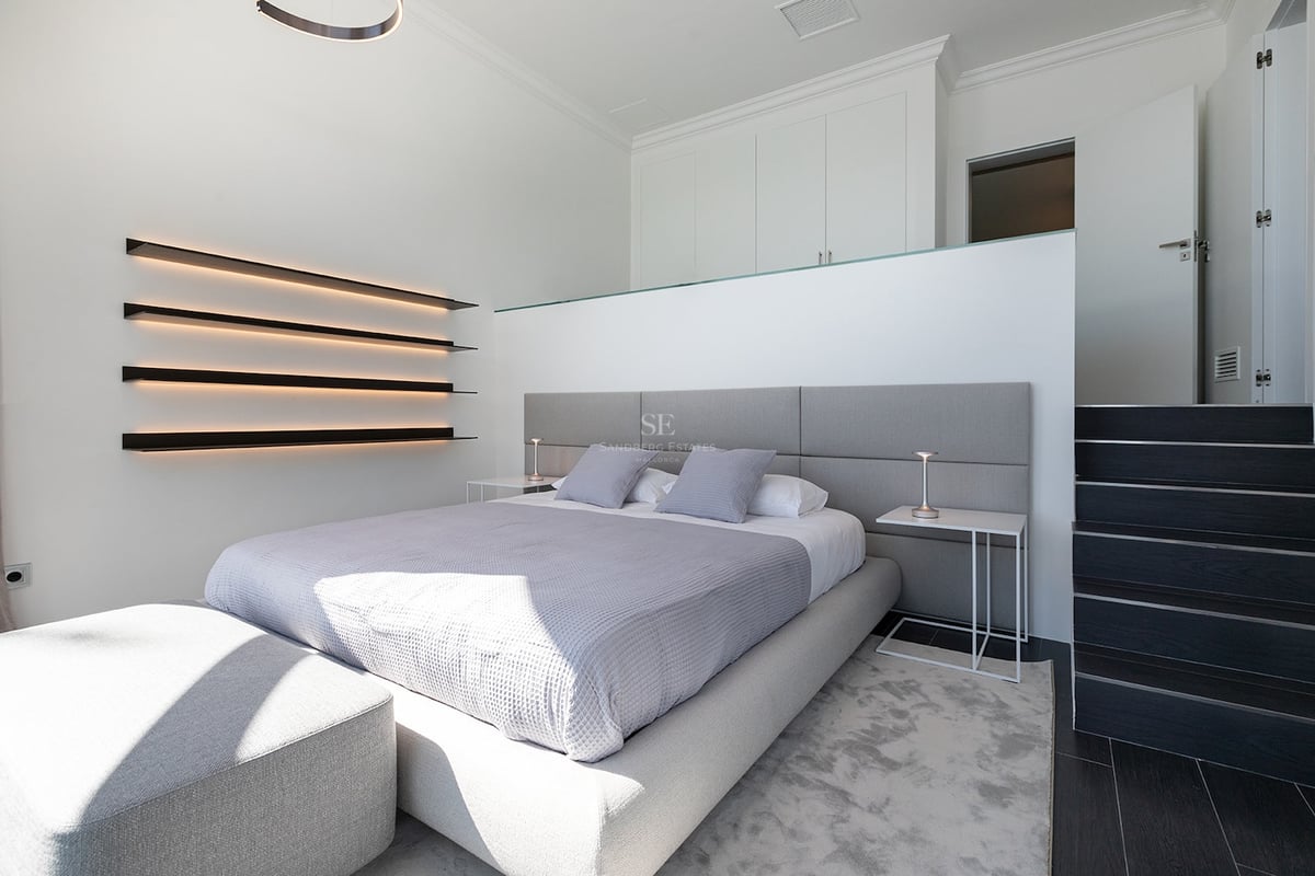 Chambre moderne avec lit gris, étagères LED intégrées et design minimaliste blanc.