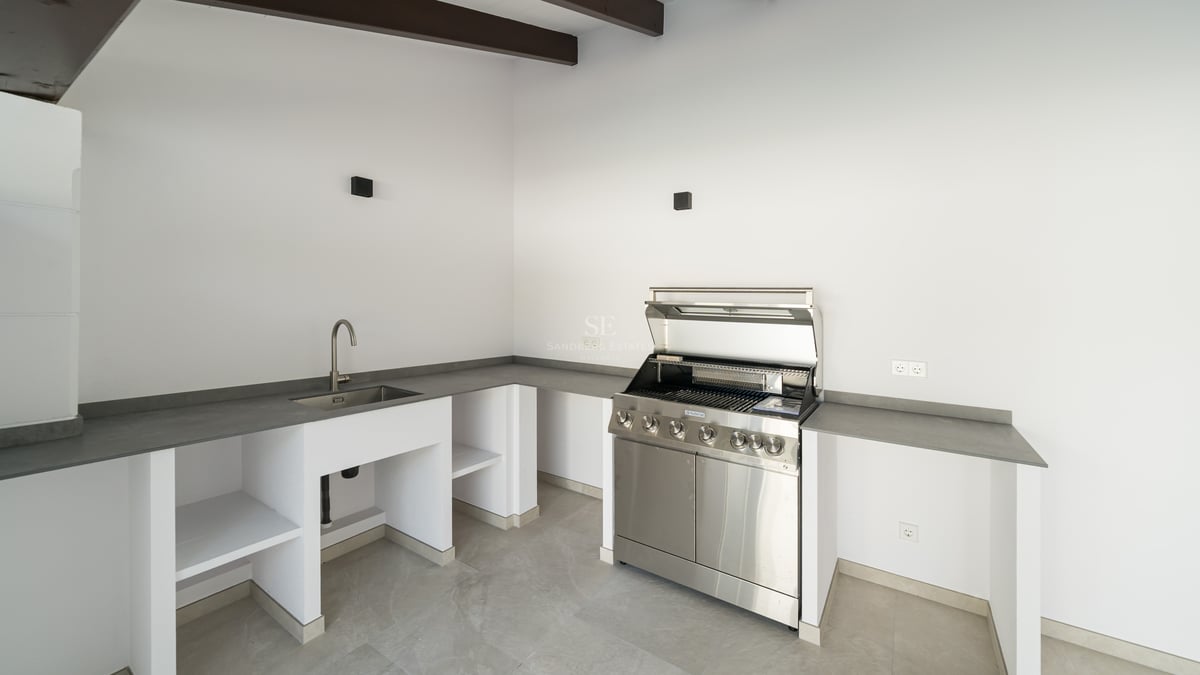 Cuisine extérieure contemporaine avec grill en inox, évier intégré et plans de travail gris.