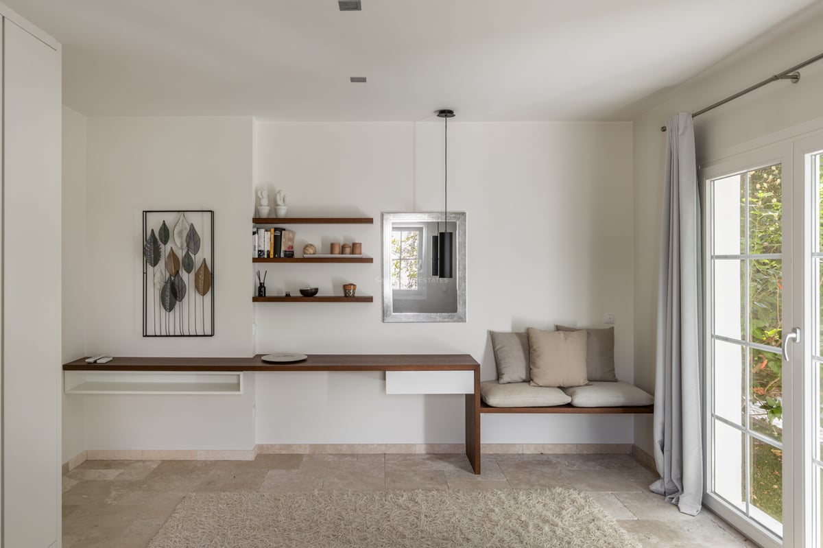 Bureau minimaliste moderne avec bureau flottant en bois, sol en pierre naturelle et banquette intégrée.