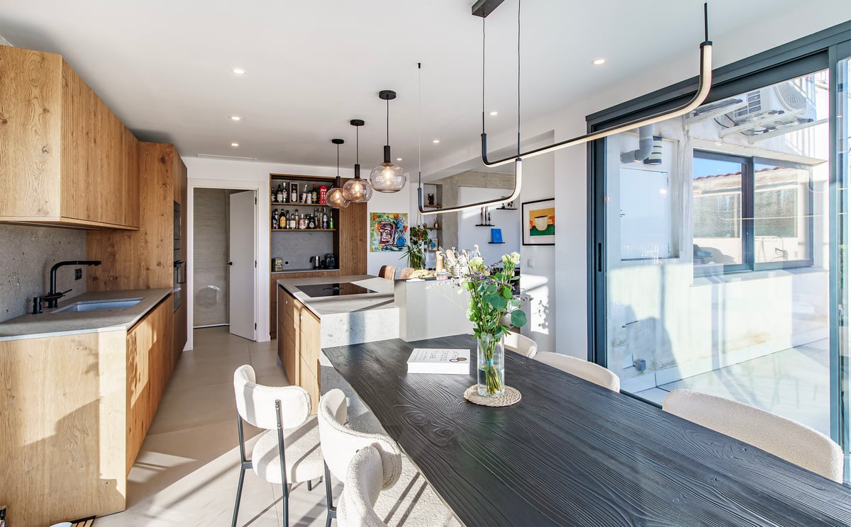 Cuisine moderne avec îlot en pierre et table à manger en bois noir avec chaises en bouclé crème.