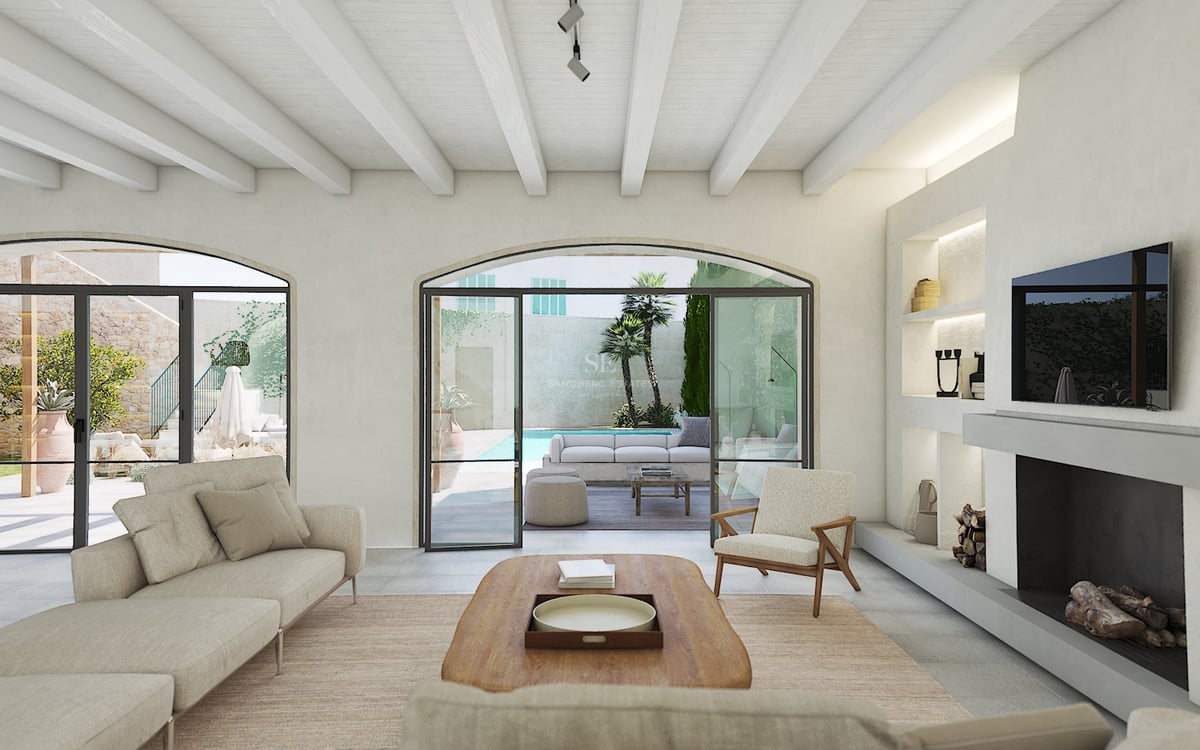 Salón elegante con techos de vigas blancas, chimenea y puertas arqueadas que dan a una piscina privada y terraza.