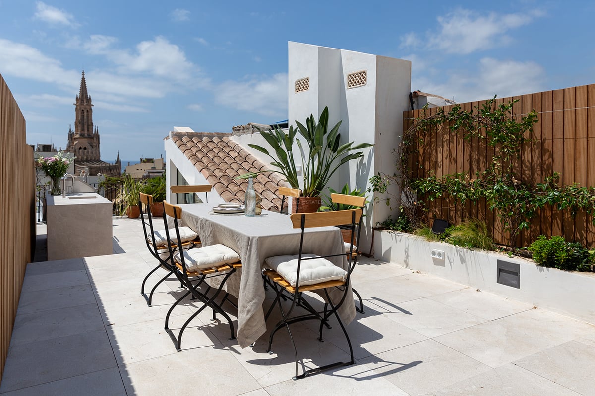 Terraza en la azotea con mesa de comedor, cocina exterior y vistas a la catedral gótica de Palma de Mallorca.