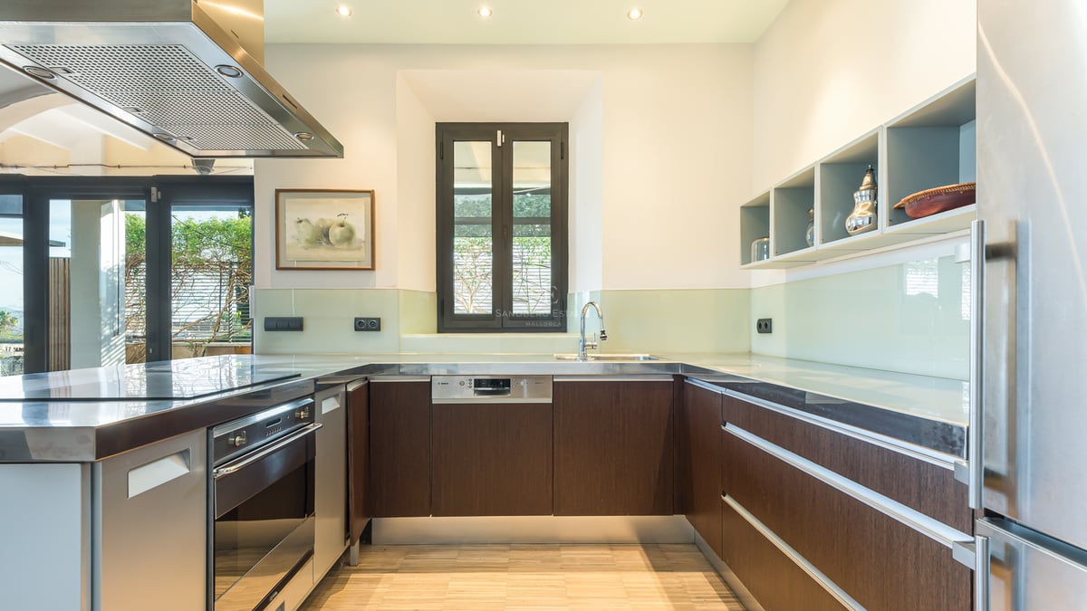 Cuisine moderne avec des armoires en bois foncé, des plans de travail en inox et une crédence en verre.