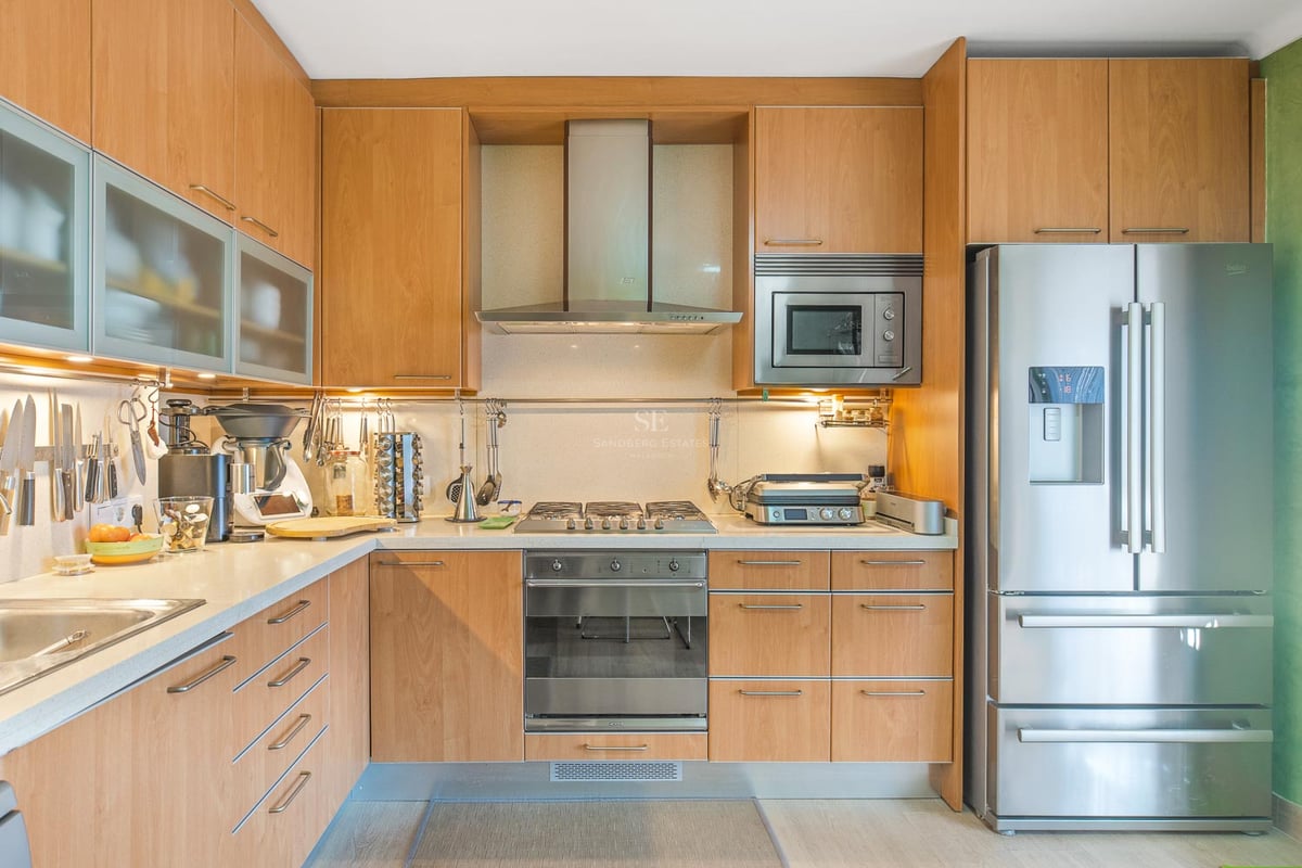 Cuisine contemporaine avec placards en bois clair, appareils en acier inoxydable et éclairage intégré.