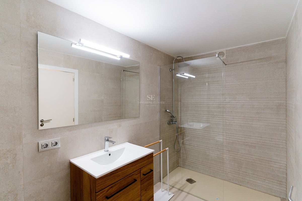 Salle de bain contemporaine avec douche à l'italienne, carrelage en pierre et meuble en bois avec grand miroir.