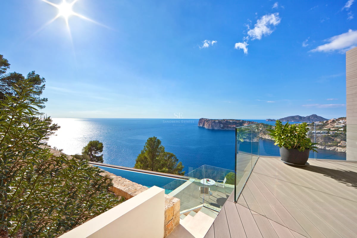 Terrasse moderne avec garde-corps en verre surplombant la mer Méditerranée et une piscine à débordement.