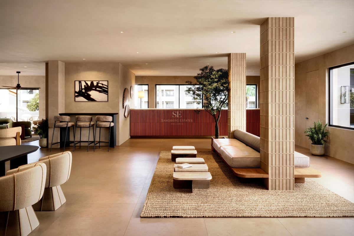 Modern lobby med räfflade pelare, låga sittmöbler, vävd matta och varma terrakottadetaljer.