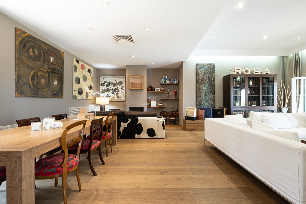 Grand salon avec parquet en chêne, art moderne, table à manger en bois et canapés blancs.