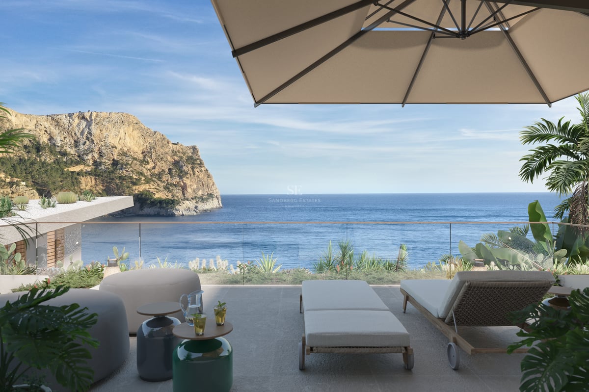 Terrasse ensoleillée avec chaises longues, parasol et garde-corps en verre surplombant la mer et une falaise.