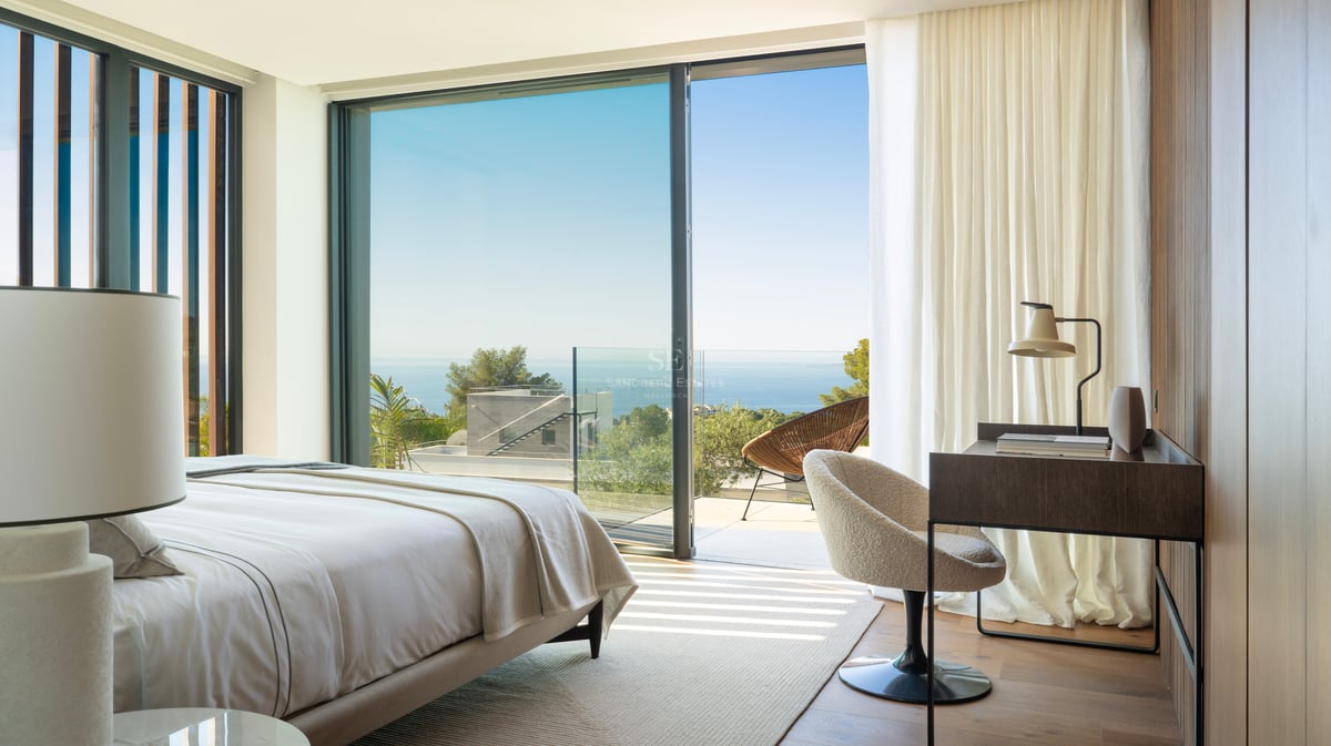 Chambre de maître moderne avec parquet, baies vitrées et terrasse offrant une vue sur la Méditerranée.
