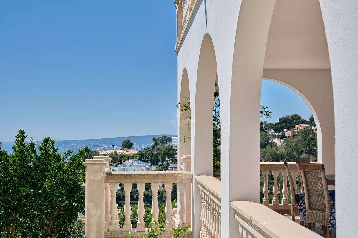 Terrasse à arches blanches et balustrade en pierre surplombant la côte et la mer Méditerranée.