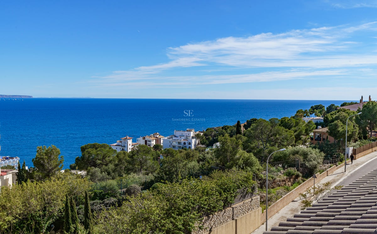 Vue panoramique surélevée sur la mer Méditerranée bleue, les pins côtiers et les villas blanches sous un ciel clair.