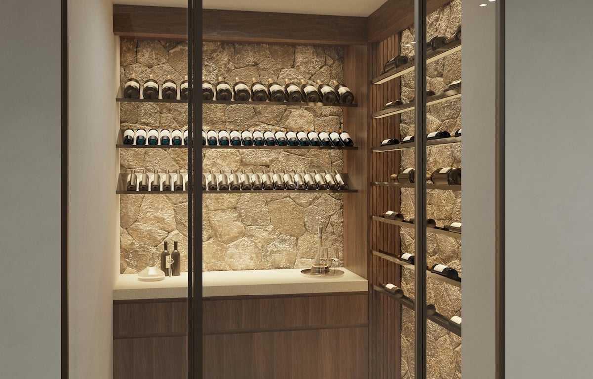 Cave à vin vitrée avec mur en pierre naturelle, étagères en bois sombre et bouteilles de vin alignées.