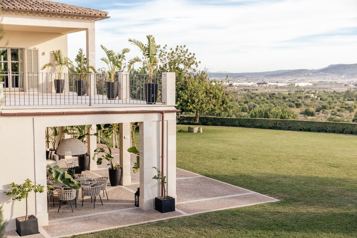 Terrasse en pierre sur deux niveaux avec coin repas extérieur, surplombant un grand jardin et des collines.