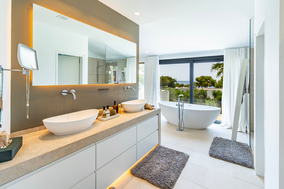 Vue extérieure d'une villa moderne avec piscine réfléchissante, larges fenêtres et design minimaliste dans des tons neutres.