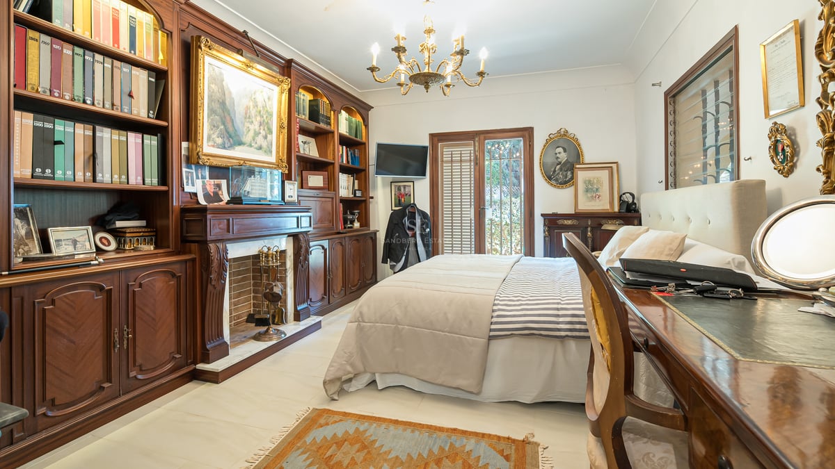 Chambre élégante avec bibliothèques en bois sombre, cheminée traditionnelle et lustre doré.