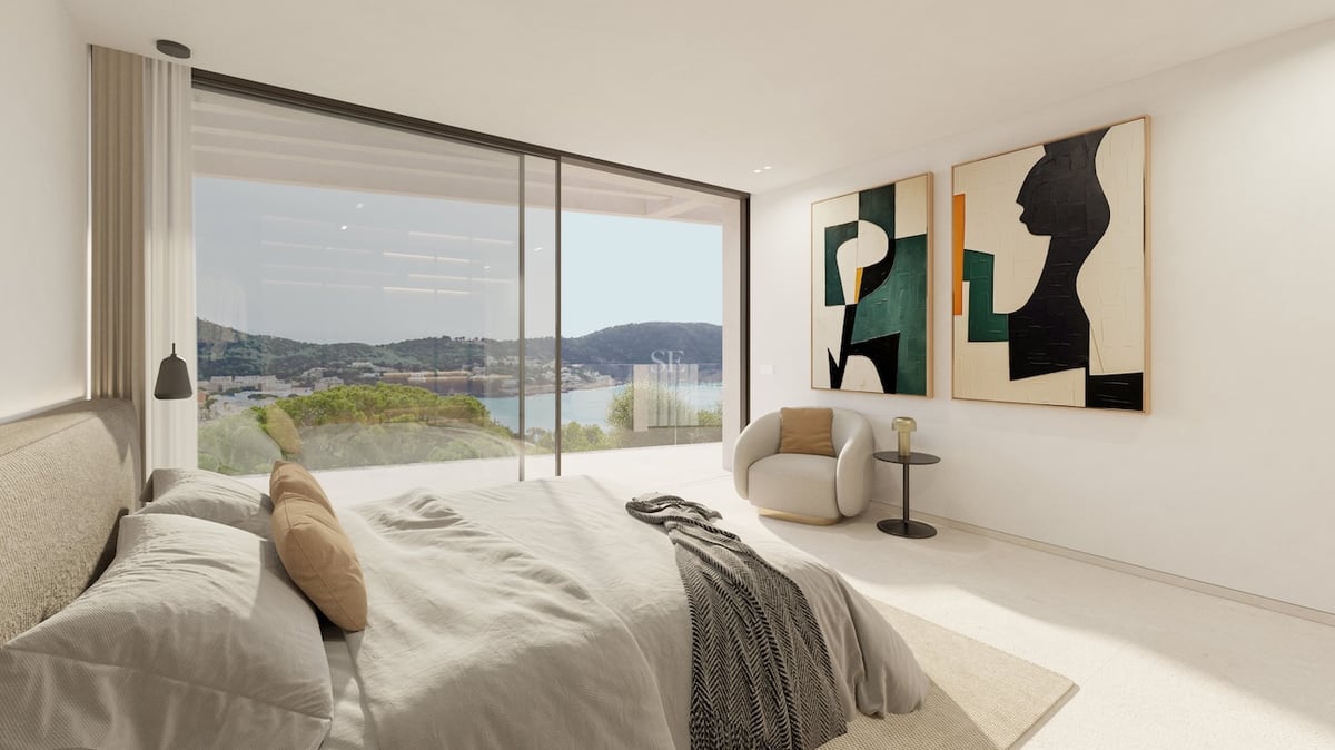 Chambre de maître moderne avec de grandes baies vitrées offrant une vue sur la côte et la mer.