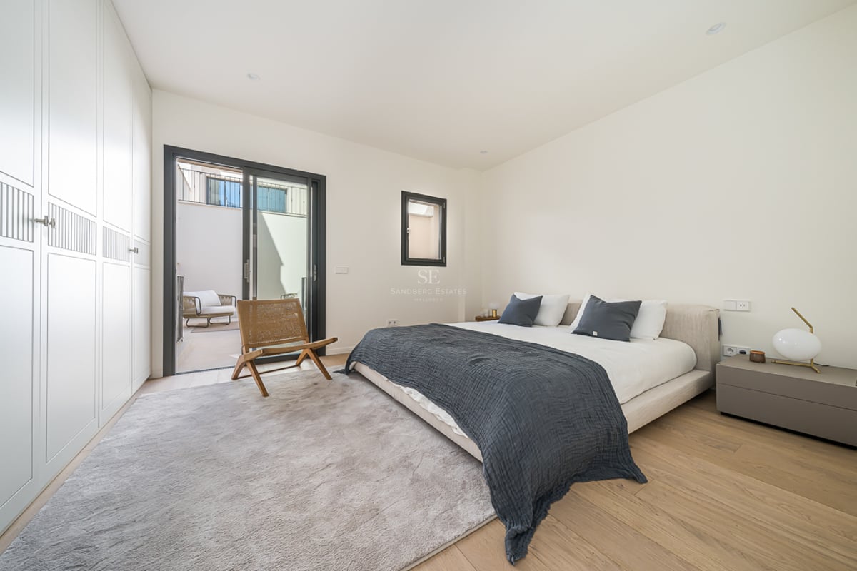 Modernes Schlafzimmer mit Doppelbett, weißen Schränken, Eichenparkett und Glasschiebetür zu einer Terrasse.