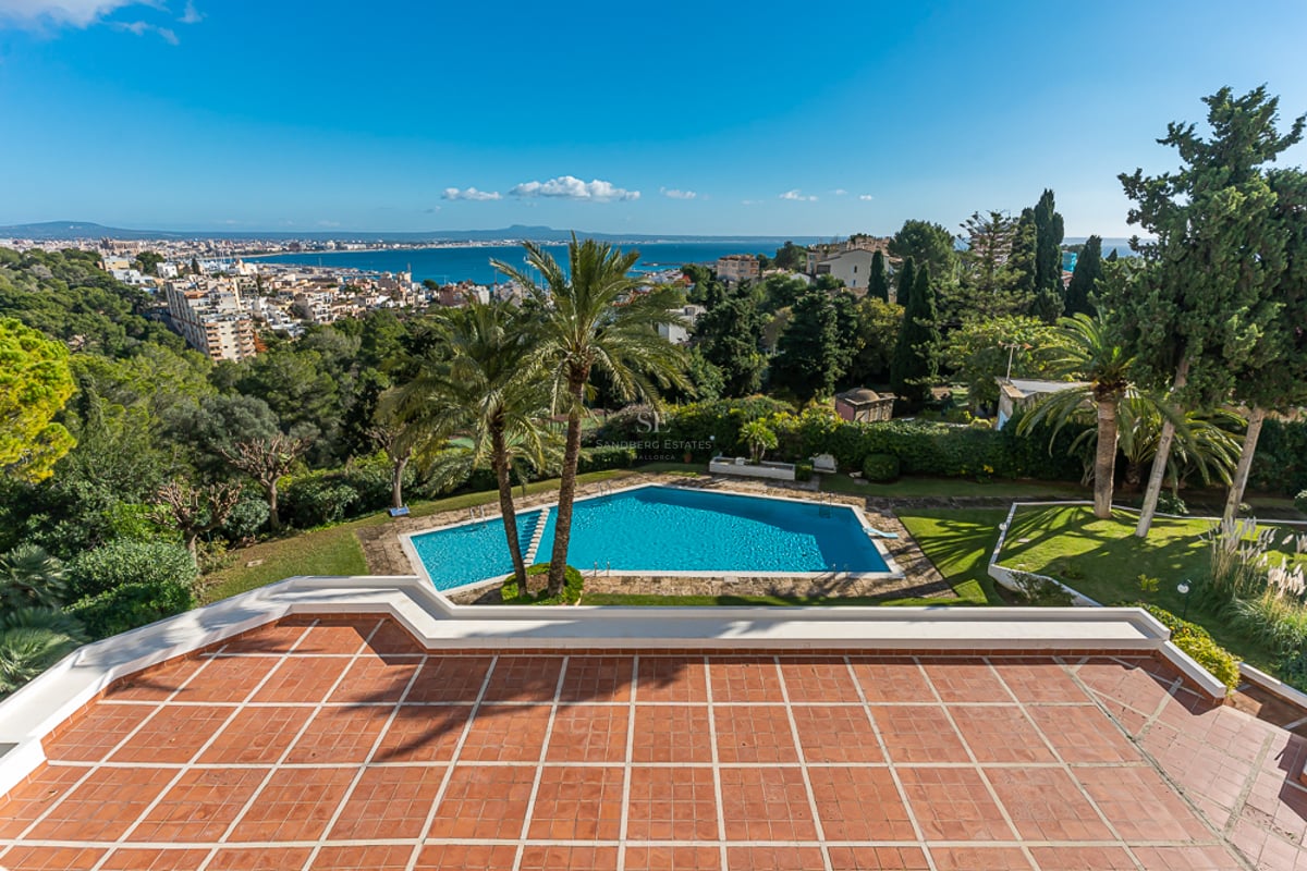 Vue de la piscine à débordement et de la villa moderne minimaliste. De larges fenêtres reflètent le ciel. Design élégant et contemporain.