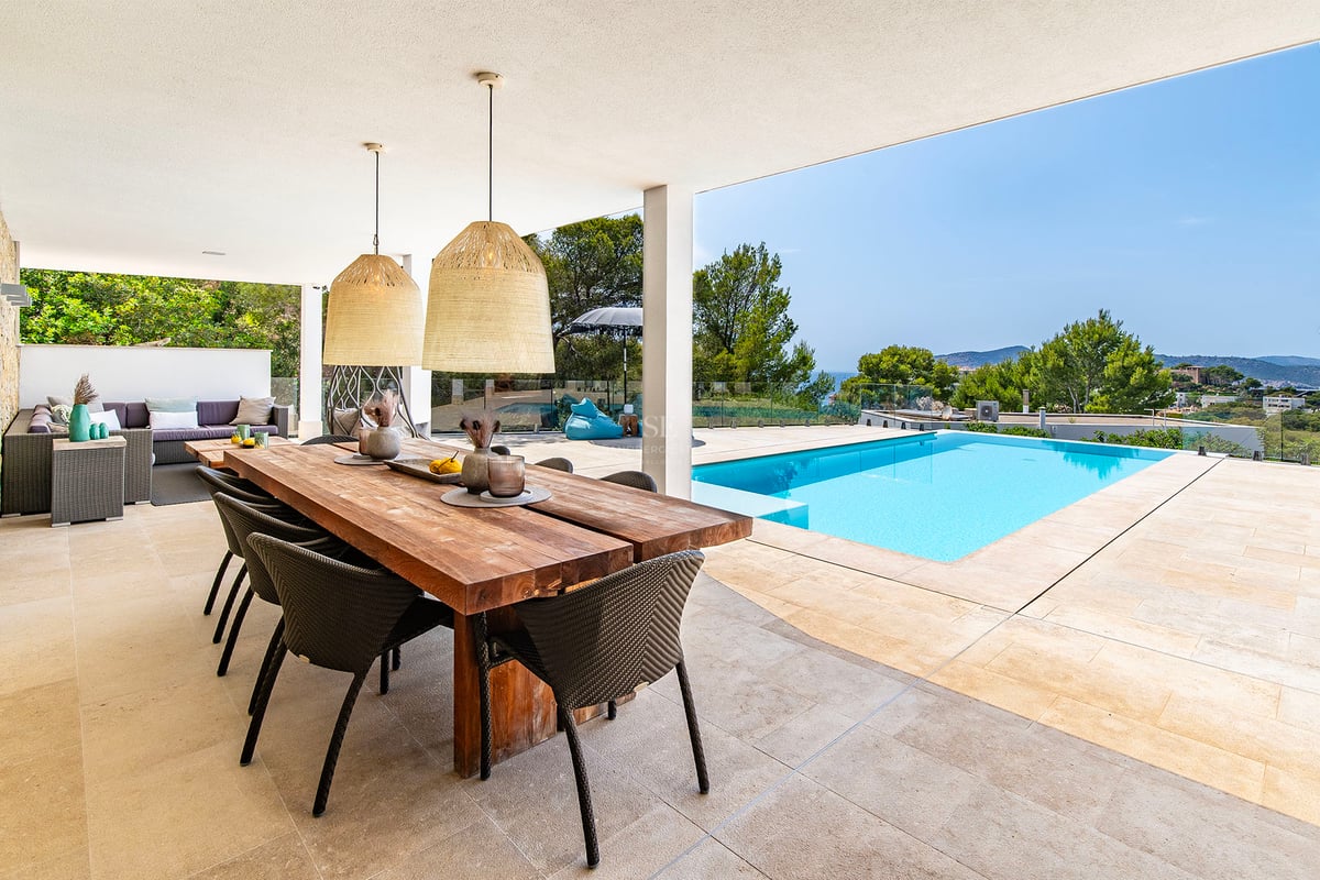 Salon spacieux avec baies vitrées, canapés beiges et table basse en bois. Vues panoramiques sur la mer depuis le balcon. Design moderne et lumineux.