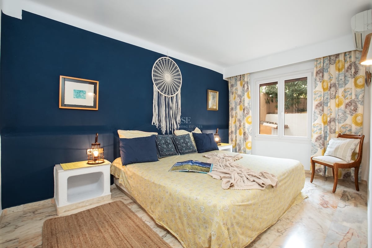 Chambre avec un grand lit, un mur d'accent bleu marine avec un attrape-rêve et un sol en marbre poli.