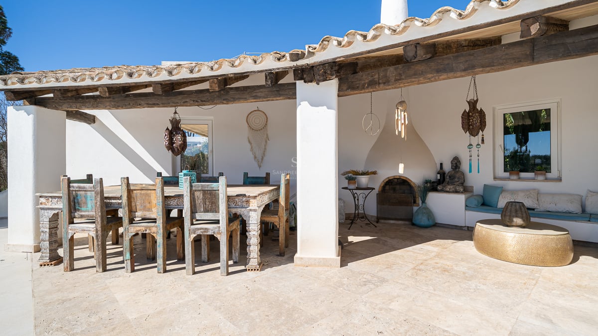 Terrasse couverte avec salle à manger en bois rustique, sol en pierre, cheminée intégrée et décoration méditerranéenne.