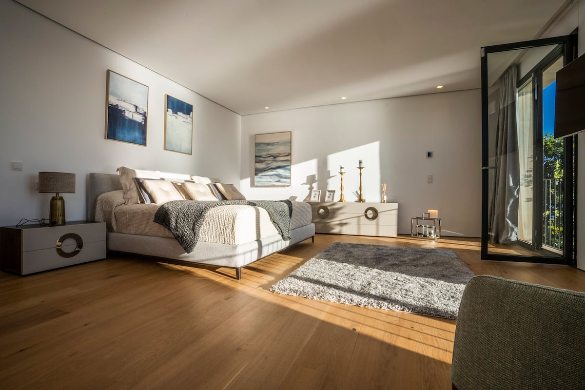 Chambre moderne spacieuse avec lit double, parquet en chêne, grande baie vitrée et lumière naturelle directe.