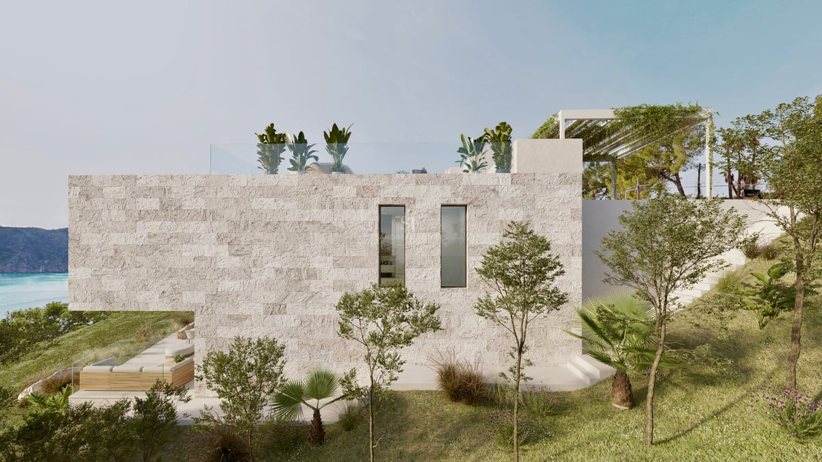 Vue latérale d'une villa de luxe avec murs en pierre texturée, terrasse sur le toit et jardin méditerranéen.